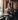 Woman sitting in a cafe holding a steaming cup of coffee wearing the Sorrento in Camo luxury Apple Watch band