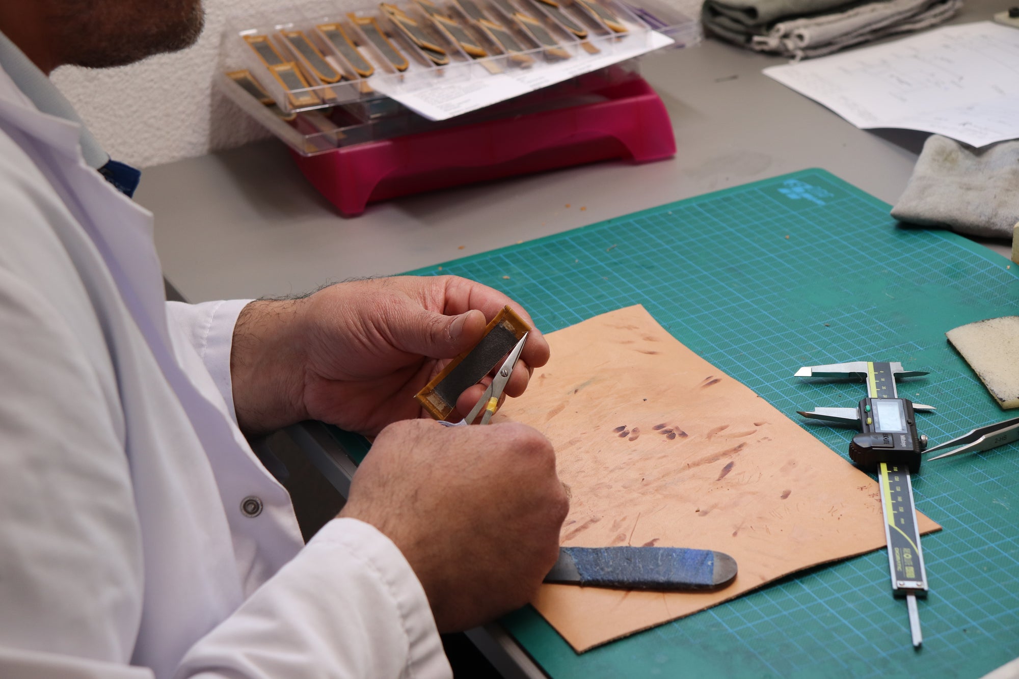 Artisan hand-cutting leather in a workshop with precision tools