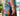 A close-up lifestyle shot of a woman wearing the Gelato in Rosewater Apple Watch band with a pleated maxi skirt with a colorful tropical beach print.
