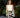 A woman stands on a sidewalk in front of a restaurant, wearing the Liquid in black Apple Watch band and a white halter crop top and a black and white abstract patterned pleated midi skirt.