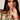 A Model wearing the Liquid in Coral patent leather Apple watch band by Chalonne with a peach blouse with a sage and coral interlocking chain pattern