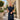 A woman wearing the Orleans in Wine Apple Watch band a dark navy dress and holding a structured navy handbag .
