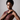 A model wearing the Sedona in Navy Apple watch band and a sleeveless, structured burgundy dress.