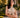 A woman wearing the Sorrento in Olive Apple Watch band and a draped beige halter dress.