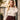 A woman wearing the Sorrento in Peacock Apple Watch band and a cream satin blouse with a bow collar and a dark burgundy wrap skirt.