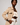 A model wearing the Waiheke in cream shearling Apple Watch band and a beige trench coat over a cream crop top and white pants